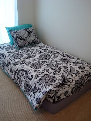 White, black and teal bed spread on bed