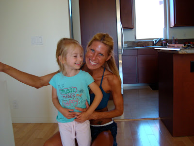 Woman in workout clothes kneeling down next to young girl smiling