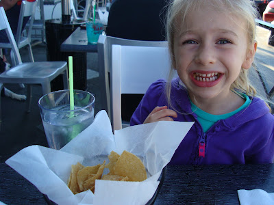 Young girl sitting with a drink and chips in front of her