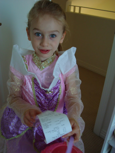 Young girl in halloween costume holding receipt 