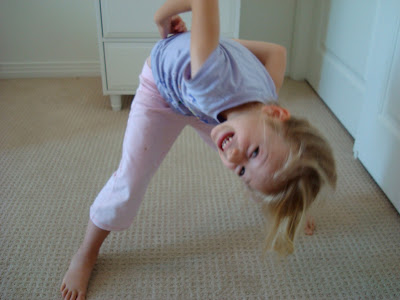 Young girl attempting to do Prasarita Podattanasana yoga pose