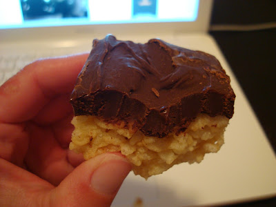 Hand holding one GF Vegan "Rice Krispie" Treat with Chocolate Peanut Butter Coconut Oil Frosting 