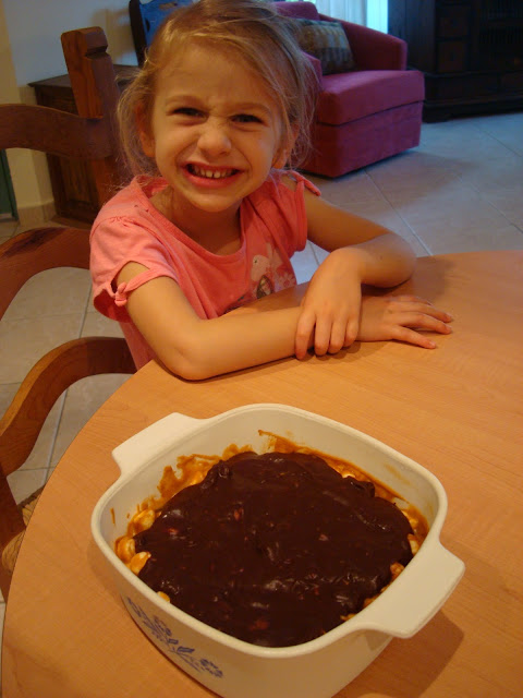 Little girl smiling with GF Peanut Butter Marshmallow Bars with Vegan Chocolate Frosting on table