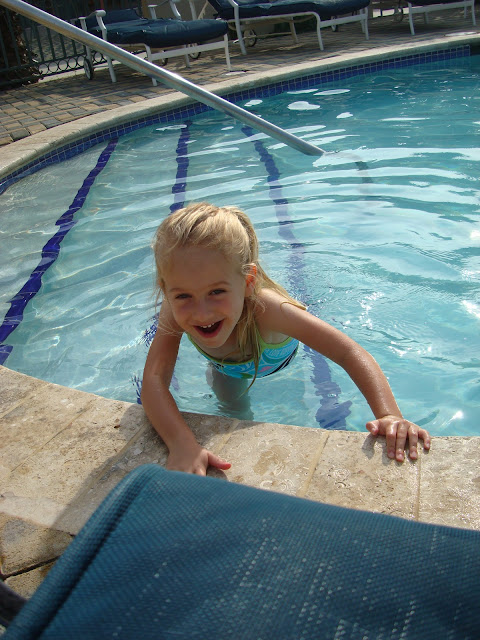 Young girl playing on pool steps holding onto side