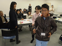 小学生の男の子が真似して歩くのにつかまって、歩き方をみています