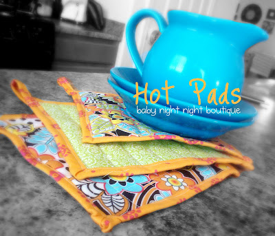 3 hot pads next to a blue pitcher on two blue plates and titled, \" Hot Pads, baby night night boutique\"