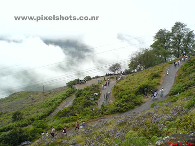 scenic mountain slope of munnar rajamala,people walking through the misty mountain road in munnar hill station kerala