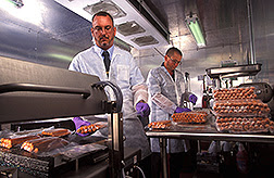 Molecular biologist Chris Sommers (left) and microbiologist Glenn Boyd vacuum-seal hotdogs to get them ready for irradiation. Photo by Stephen Ausmus.