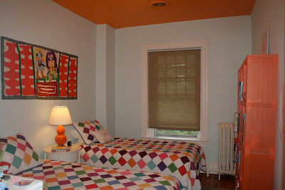 light blue bedroom with orange ceiling and colorful quilts