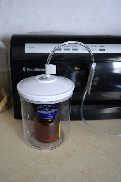 A recycled jar with lid inside a FoodSaver canister attached to a FoodSaver appliance.