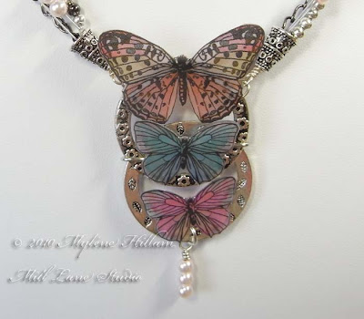 Mixed Media Butterfly Necklace featuring butterflies cut out from scrapbook paper which were then coated with resin. Includes a tutorial on how to create your own epoxy resin stickers by Myléne Hillam of Mill Lane Studio.