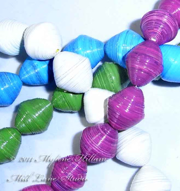 Strands of colourful paper beads in fuchsia, bright green, turquoise and white