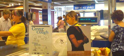Cashier at Ikea. Sign in the foreground shows a young woman's body with no head, and the neck lines up with the actual head of the cashier