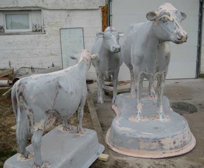 Three gray fiberglass cows in varying sizes