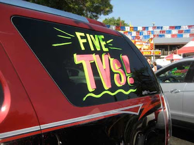 Back of an SUV painted with a sign that says FIVE TVs!