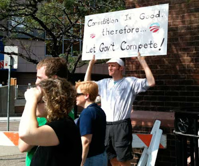 Man with sign reading Competition is good therefore...Let Governmentt Compete!