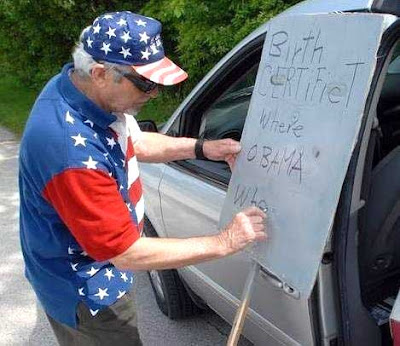 Man writing sign that says Birth certifict where Obama...