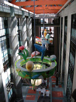 Colorful sculpture hanging high above an atrium that goes down five or six floors