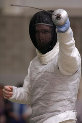 Jimmy Fruchterman in fencing gear, his face partially visible through the mask, holding his foil in front of him