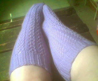 Lilac knee socks on feet to display cabled eyelot pattern