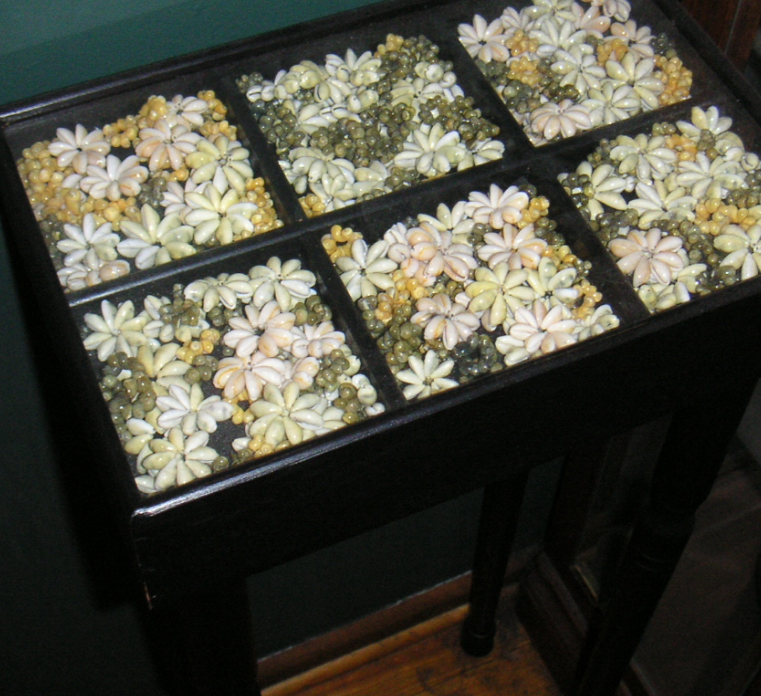 a display case made into a table filled with seed lei pieces