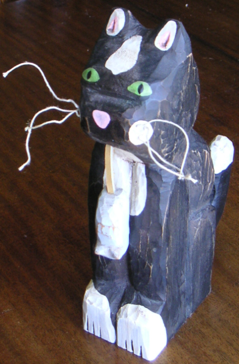 carved cat holding a grey carved mouse