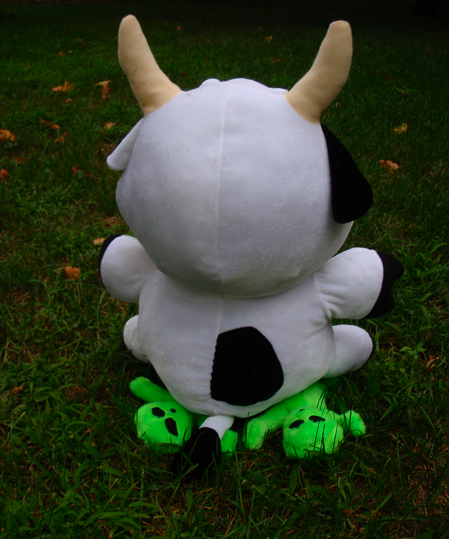 stuffed cow sitting on stuffed aliens