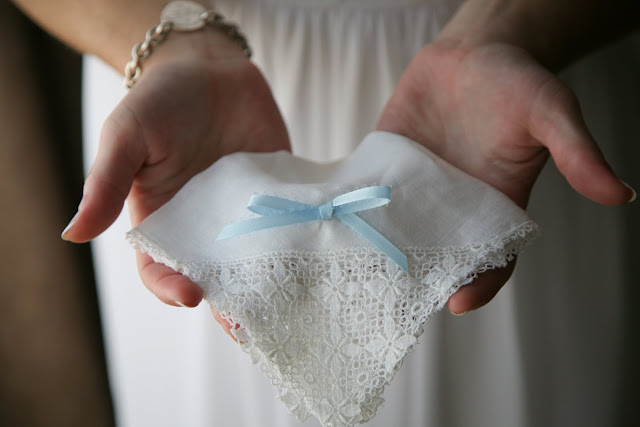 Bride holds handkerchief with blue ribbon on her wedding day