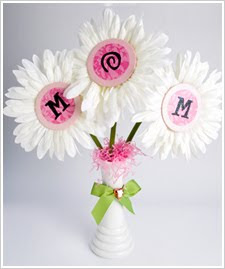Three fake flowers in a vase with their centers spelling mom