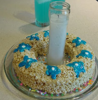 Rice Krispie Cake circle with blue frosting flowers and a candle in the center