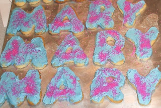 Cookies spelling mary frosted with blue frosting and pink sugar sprinkles