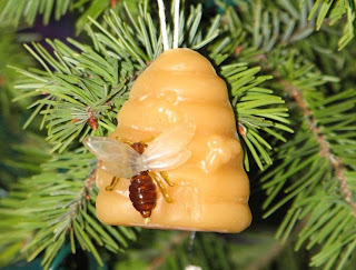 Wax ornament of a beehive with a bee on it hung on a tree.
