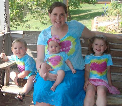 Mom and children wearing tie-dyed shirts on wooden swinging bench