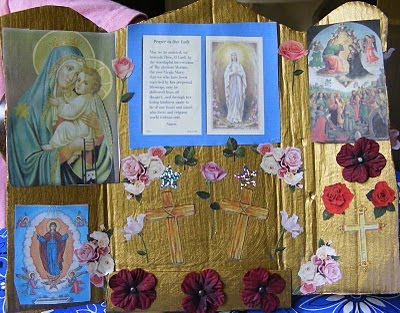 Gold painted cardboard triptych with picture of Mary and text about her.