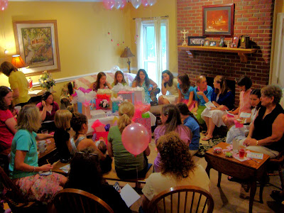 Guests at a baby shower sitting in a living room around the mother with her gifts