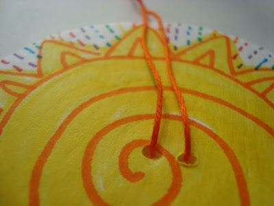 Sun-patterned foam board with two orange yarn strings through them