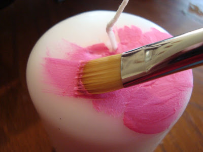 Paint brush painting wax on top of a candle