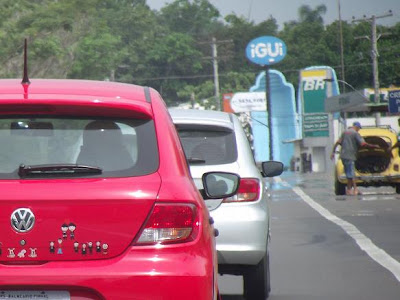 tráfego de veículos Wolkswagen na RS-040 sentido Porto Alegre, chamada de Forno Alegre pelos porto alegrenses no verão, em direção ao Litoral Norte do Estado do RS em um dia quente de verão. No acostamento, fusca amarelo com problemas mecânicos. A foto mostra ainda miragem causada pelas ondas de calor no asfalto