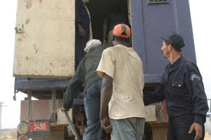 Migranti caricati sui camion della polizia per l'espulsione