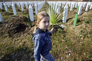 A Bosniak girl carries a leaf to decorate a grave of her relative buried at a cemetery in Potocari among other victims of the 1995 Serb massacre of 8,000 Muslims in the former U.N. 'safe area' Srebrenica February 24, 2007.