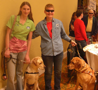 Picture of Toby & I, with Kathy Champion & Angel. Both dogs are staring straight at each other. Angel is dark yellow