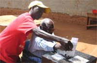 Old man assisted to cast ballot and elect election candidate
