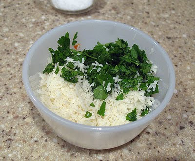 A bowl of Parmigiano-Reggiano and chopped Italian parsley leaves.