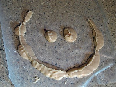 A photo of extra batter on a sheet of parchment paper in the shape of a smiley face.