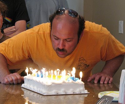 A photo of Amanda\'s friend Pete blowing out candles on a birthday cake.