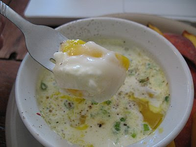 A photo of a spoonful of eggs baked in ramekins with herbs.