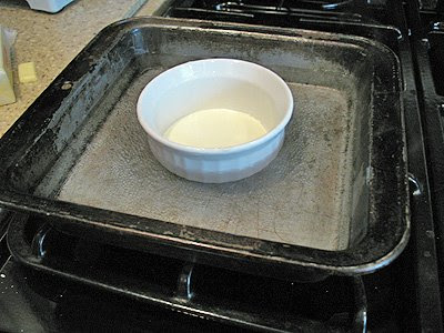 A photo of a ramekin in a pan on the stove.