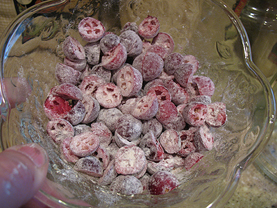 A close up photo of cranberries in a bowl tossed with a tablespoon of the flour mixture.