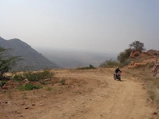 Arun riding the KTM Duke up the muddy, off-road path toward the fort