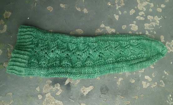 A sock laying flat, with the top of the foot visible.  The heel is not visible.  A lace pattern goes from the top of the cuff to the toe.